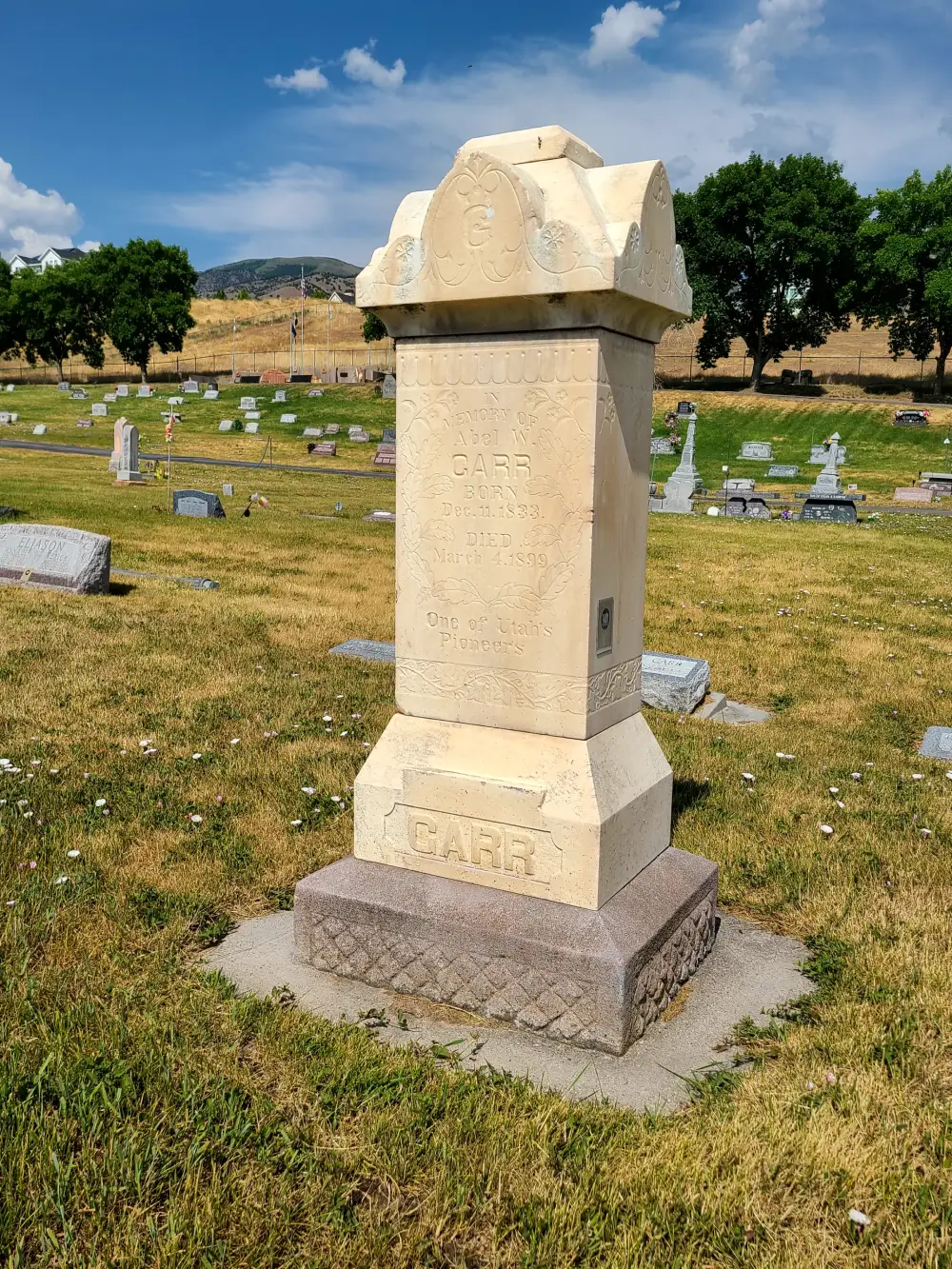 Tall cemetery tombstone under blue sky.
