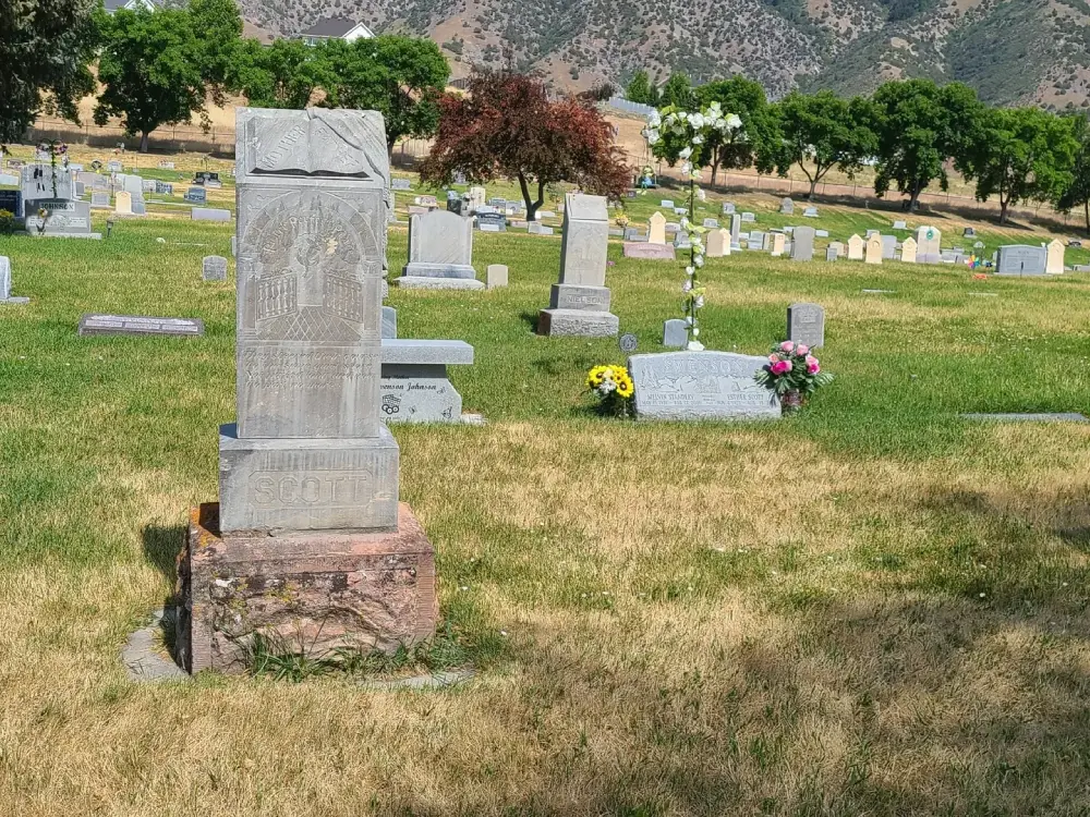 Gravestones in a cemetery with flowers.